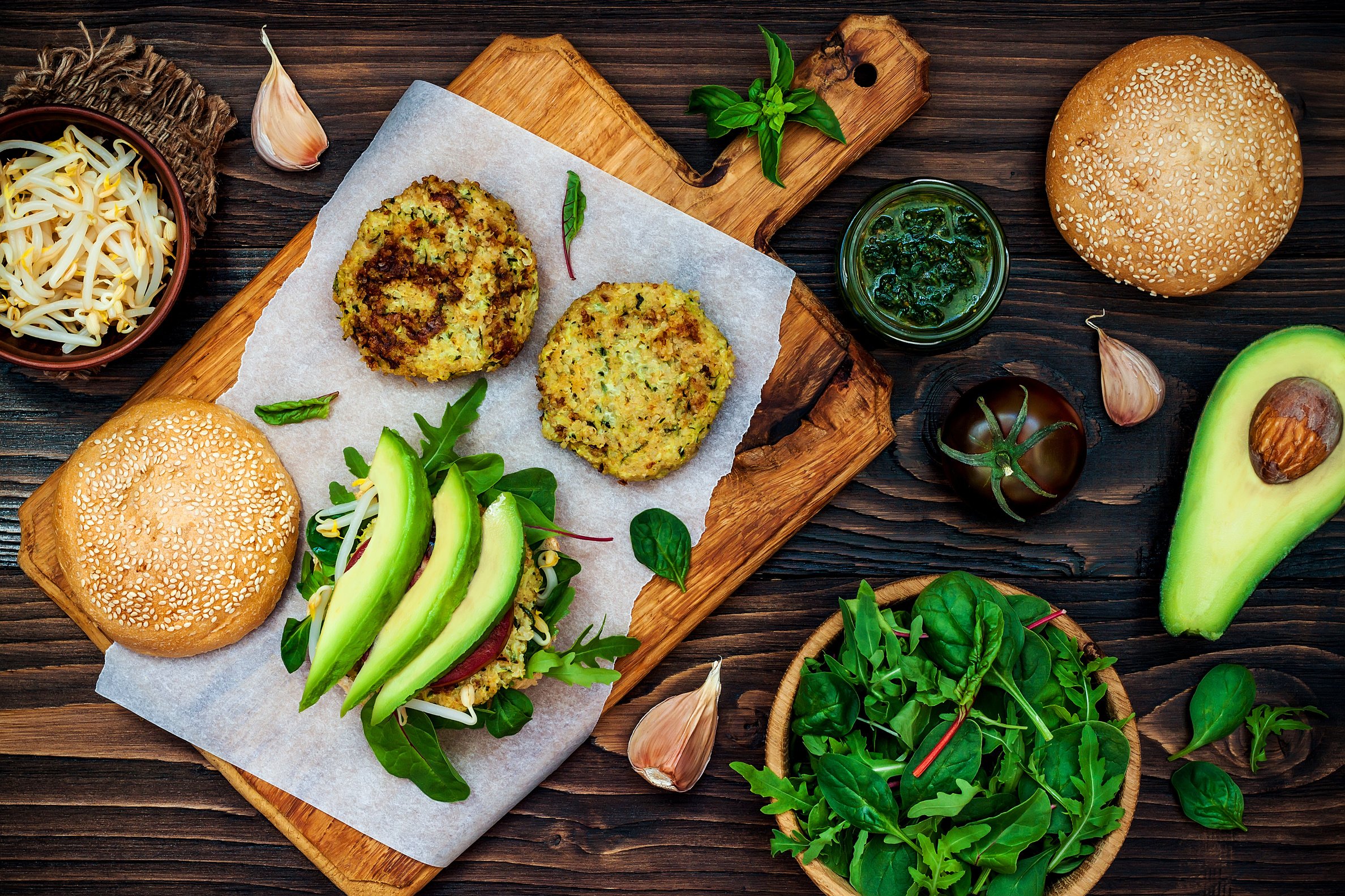 Zucchini quinoa veggie burger with pesto sauce and sprouts.